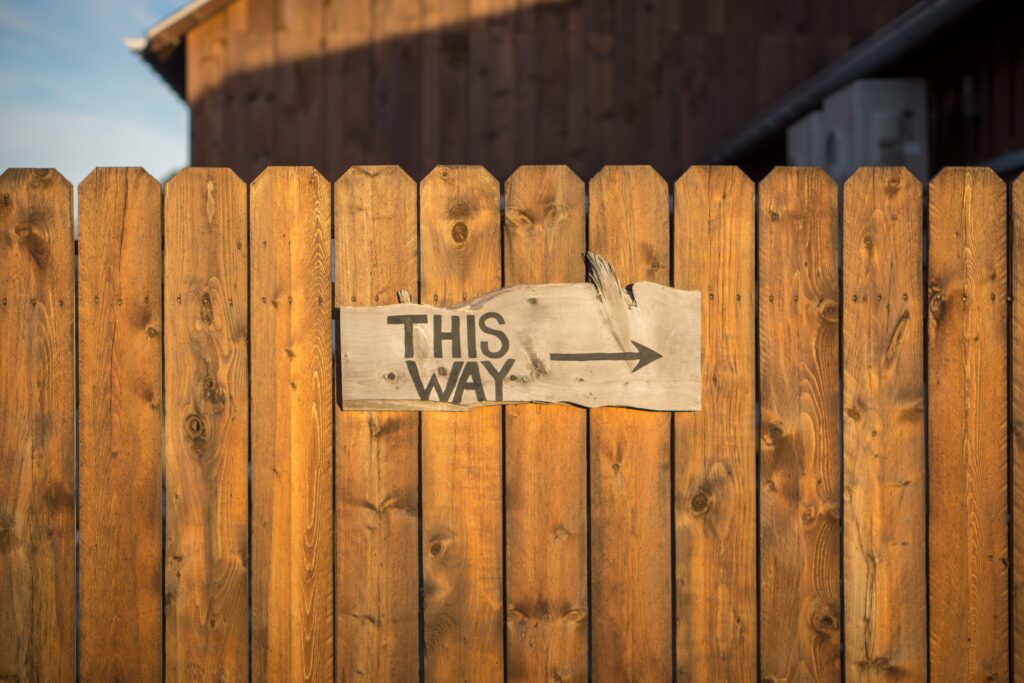 A sign on a wooden fence that says "This way", pointing to the right Photo by Jamie Templeton on Unsplash